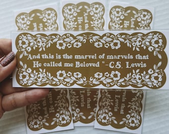 May include: Gold bookmark with a white floral border and the quote "And this is the marvel of marvels that He called me Beloved" - C.S. Lewis.