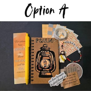 May include: An assortment of religious-themed stationery and accessories. Includes a journal with a lantern design, a yellow pen, a bookmark with text, a bracelet with the word "JESUS", and various decorative paper pieces.