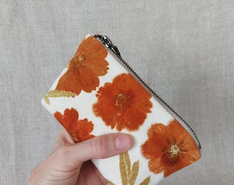 Monedero pequeño con cierre de cremallera y diseño ecoprint con plantas de flores cosmos.