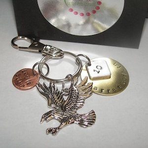 May include: A silver eagle charm, a copper charm with the text "Eagle Scout", a silver charm with the number "10", and a brass charm with the text "Barrett Boy 10" attached to a silver key ring.