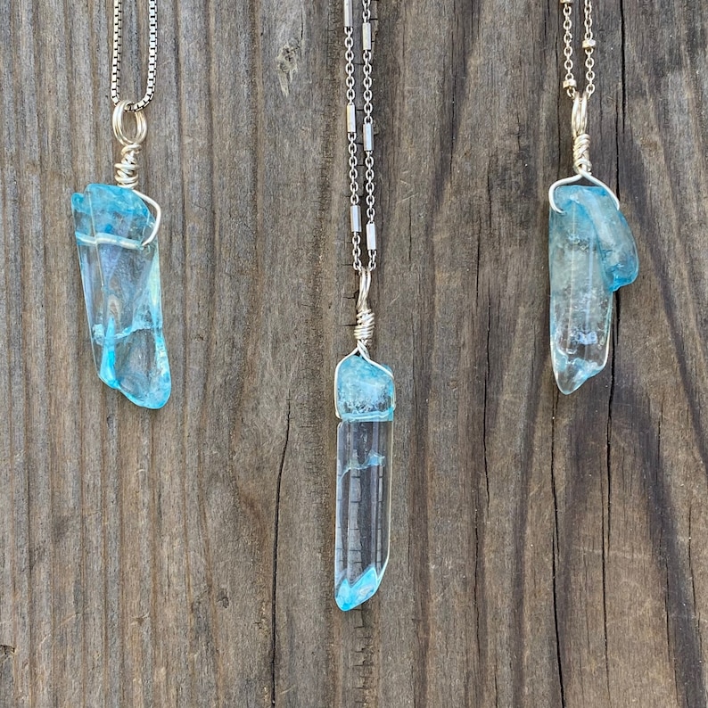 Puede incluir: Tres collares de plata con colgantes de cristal azul. Los cristales son largos y delgados, parecidos a fragmentos de hielo.