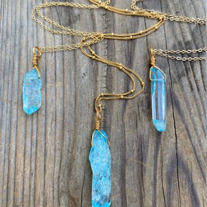 Puede incluir: Tres collares de cadena dorada con colgantes de cristal azul. Los cristales est&aacute;n envueltos en alambre dorado y tienen una textura rugosa y natural.