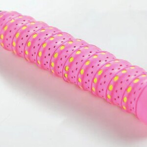 May include: Pink and yellow badminton racket grip with a textured surface and small holes. The grip has a logo on the end.