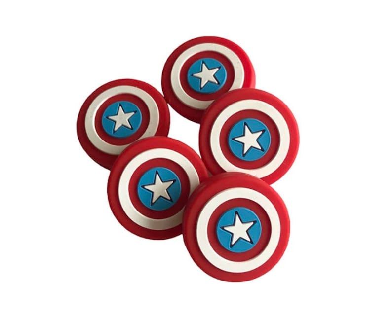May include: Six red, white, and blue plastic Captain America shield-shaped buttons. Each button features a white star on a blue circle in the center of the shield.