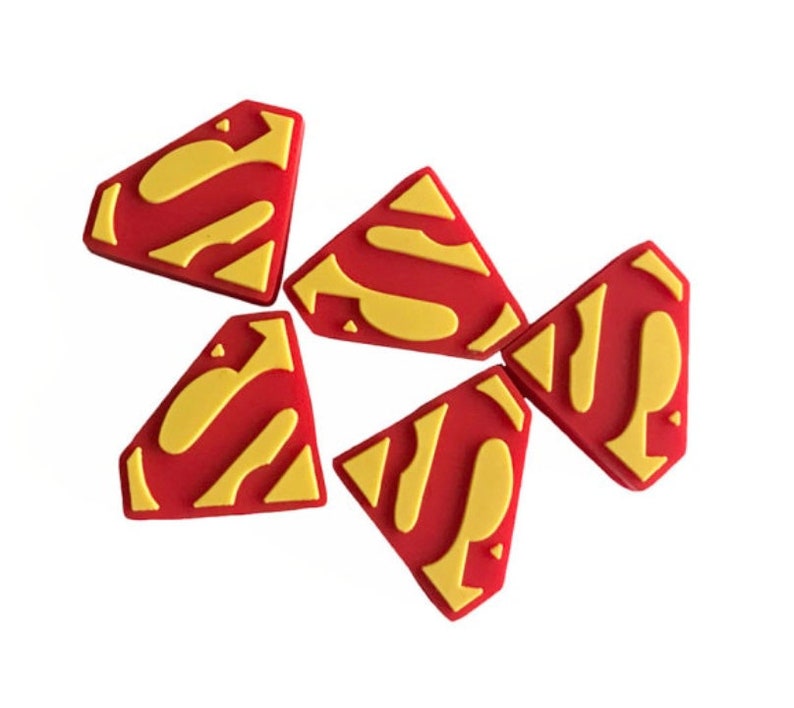 May include: Five red and yellow rubber Superman logos. The logos are shaped like a diamond with a rounded top and bottom.