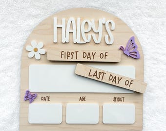 May include: An arched wooden sign featuring the name HALEY'S in white 3D letters. It includes a white daisy, two purple butterflies, and text reading FIRST DAY OF and LAST DAY OF. Three white rectangular spaces are provided for date, age, and height.