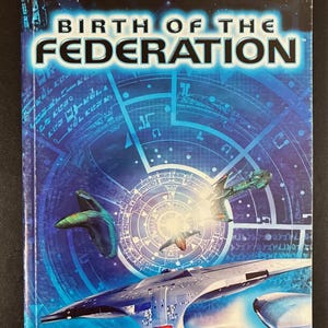 May include: A Star Trek The Next Generation Birth of the Federation game manual with a blue space background featuring a large starship in the foreground, two smaller ships, and a circular graphic design. The MicroProse logo is at the bottom.