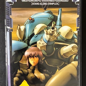 May include: DVD case for the anime series "Ghost in the Shell: Stand Alone Complex." The cover features a female character and a large, blue robotic figure. The text "Television Series Chapter 1-26" is visible.