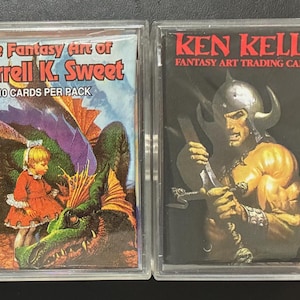 May include: Two trading card packs in clear plastic cases. One pack is labeled "The Fantasy Art of Darrell K. Sweet" with a fantasy illustration. The other pack is labeled "KEN KELLY FANTASY ART TRADING CARDS" with a warrior illustration.