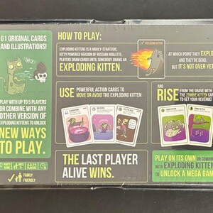 May include: Exploding Kittens card game box. The box features illustrations of cartoon kittens and text that reads "Exploding Kittens" and "New Ways to Play." The game is for 2-5 players and is family-friendly.