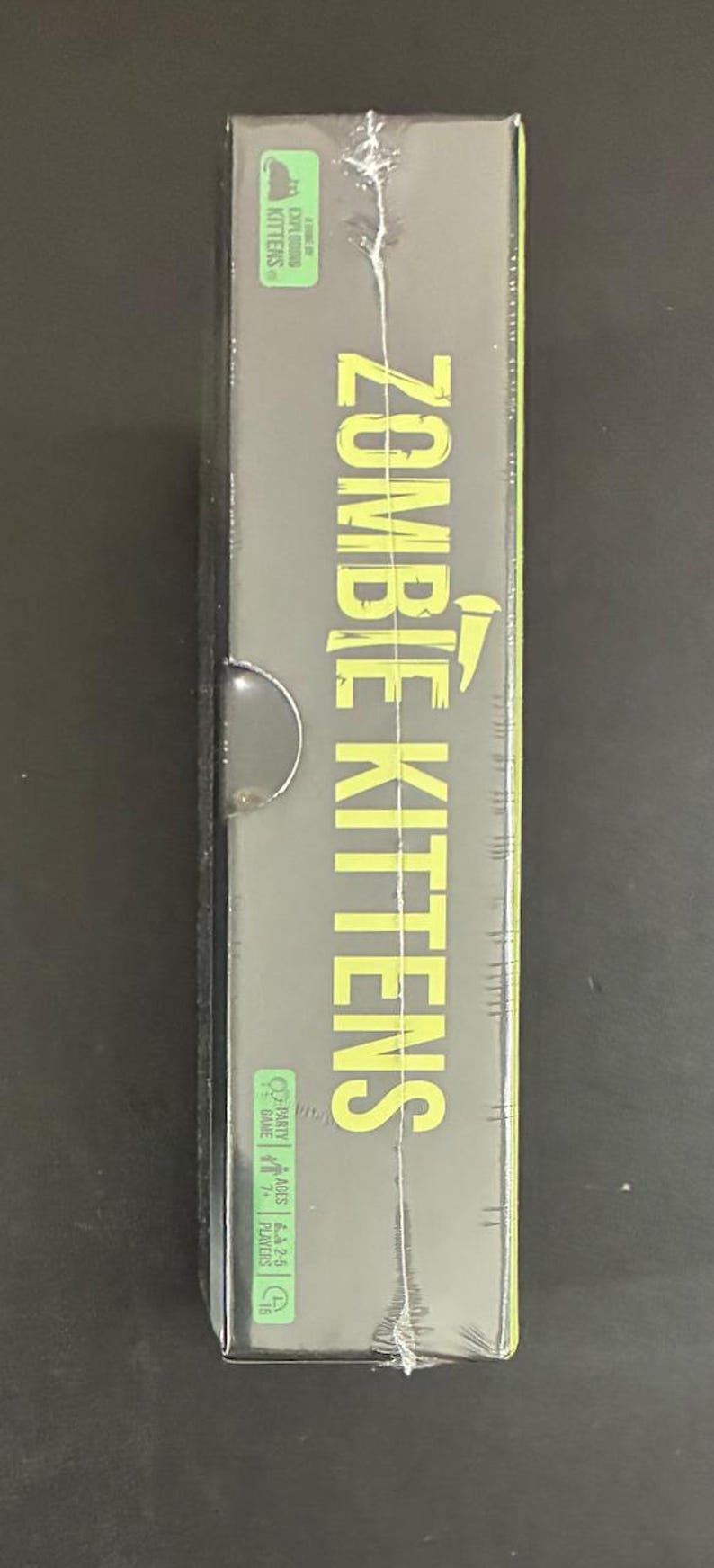 May include: A sealed box for the card game "Zombie Kittens." The game title is in large, yellow-green letters. The box is black with green accents and includes the "Exploding Kittens" logo.