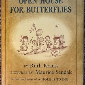 May include: A hardcover book titled Open House for Butterflies by Ruth Krauss with pictures by Maurice Sendak. The tan cover features a brown ink illustration of children playing with a drum, a balloon, and a small wagon, plus a small dog.