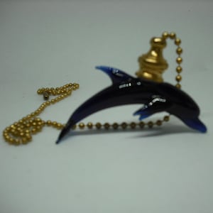 May include: A blue dolphin shaped light pull with a gold chain and a gold finial.