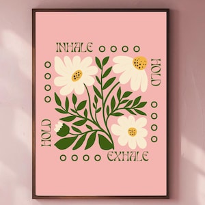 Może przedstawiać: Oprawiony wydruk artystyczny z różowym tłem, przedstawiający białe stokrotki i zielone liście. Słowa "INHALE", "HOLD" i "EXHALE" są wydrukowane, promując uważność.