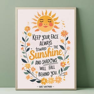 Puede incluir: Impresión artística enmarcada con un diseño alegre. La obra presenta un sol sonriente, detalles florales y la cita "Keep your face always toward the sunshine and shadows will fall behind you." de Walt Whitman.