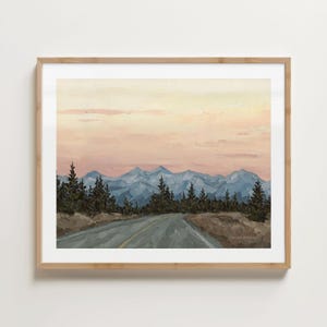 Könnte beinhalten: Gerahmtes Landschaftsgemälde, das eine Bergkette unter einem pastellfarbenen Himmel zeigt. Eine Straße führt zu den Bergen, mit immergrünen Bäumen an den Seiten. Das Kunstwerk befindet sich in einem Holzrahmen.