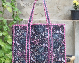 Op de afbeelding: Een grote draagtas met een bloemenpatroon in marineblauw, roze en lichtblauw. De tas heeft roze randen en handvatten. De tekst "Neelgararts" is zichtbaar.