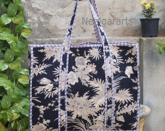 Op de afbeelding: Een grote zwart-witte tote bag met een bloemenpatroon. De tas heeft een brede basis en twee lange hengsels. De tas is gemaakt van een gewatteerd materiaal.