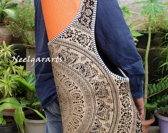 May include: A yoga mat carrier bag with a detailed black and tan mandala design. The bag has a wide strap with a black and white striped border. An orange yoga mat is visible inside the bag. The text "Neelgararts" is in the image.