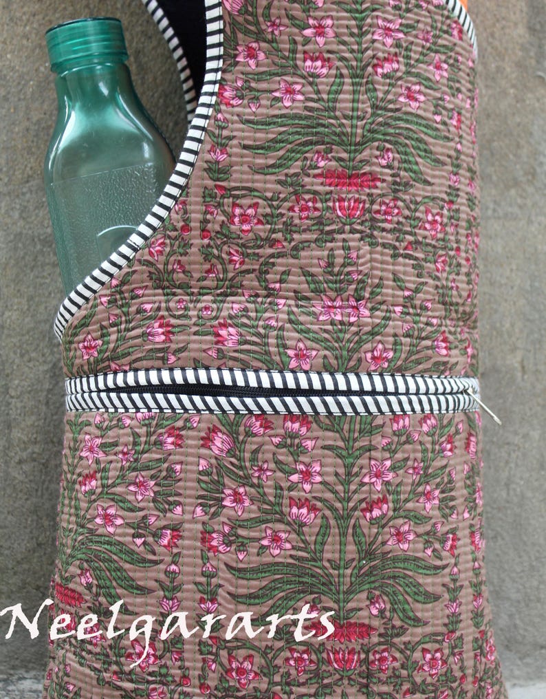 K&ouml;nnte beinhalten: Ein brauner, gesteppter Wasserflaschentr&auml;ger mit einem Blumenmuster in Rosa und Gr&uuml;n. Der Tr&auml;ger hat eine schwarz-wei&szlig; gestreifte Bord&uuml;re und h&auml;lt eine gr&uuml;ne Glasflasche. Der Text "Neelgararts" ist sichtbar.