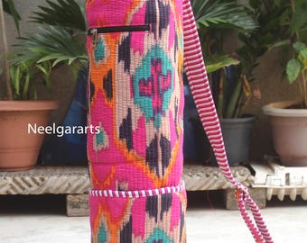 May include: A vibrant yoga mat bag with a colorful geometric pattern in pink, orange, teal, and purple. The bag has a drawstring closure, a zippered pocket, and a striped shoulder strap. The text "Neelgararts" is visible on the side.