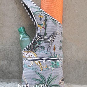 Puede incluir: Bolsa gris para esterilla de yoga con estampado de animales de la jungla, que contiene una esterilla de yoga naranja y una botella verde. La bolsa tiene un bolsillo con cremallera y un ribete a rayas blancas y negras. El texto "Neelgararts" es visible.