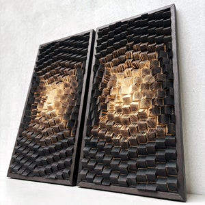 May include: Two black framed wall sculptures made of wood with a 3D geometric pattern. The wood is stained in a gradient of black and brown, creating a unique and modern look.