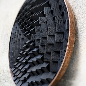 May include: A circular wall art piece made of black wooden blocks arranged in a geometric pattern. The blocks are set in a circular wooden frame.