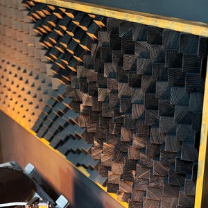 Peut inclure: Un panneau mural encadré composé de blocs de bois dans un motif géométrique. Le panneau est en bois foncé et possède un cadre en bois clair.