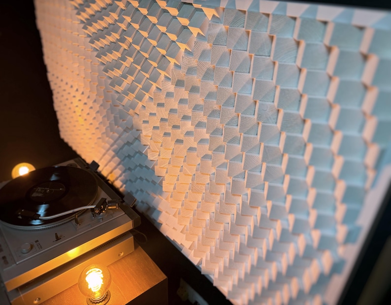 May include: A modern turntable with a black vinyl record playing, positioned in front of a large, textured wall panel made of light-colored wooden blocks. The scene is illuminated by warm, ambient lighting.