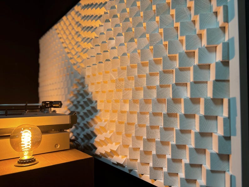May include: A wooden wall panel with a repeating pattern of square blocks, creating a textured surface. The panel is lit with warm light, and a vintage record player and a glowing Edison bulb are in the foreground.