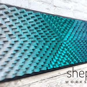 May include: A large, abstract wall art piece made of wood blocks in shades of blue and green. The blocks are arranged in a geometric pattern, creating a 3D effect. The piece is framed in black and has the text "shepit WORKSHOP" in the lower right corner.