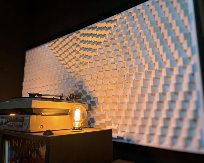 May include: A light-filled room with a vintage turntable, a decorative light bulb, and a large, textured wall panel. The wall panel is made of small, square, white blocks arranged in a repeating pattern. The scene evokes a retro aesthetic.