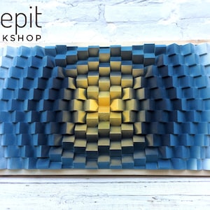 May include: A 3D wall art piece made of wood with a gradient of blue and yellow squares. The squares are arranged in a pattern that creates a sense of depth and dimension. The piece is framed in wood and has the text "shepit WORKSHOP" at the top.