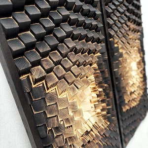 May include: Two wooden wall art pieces with a geometric pattern of dark brown and light brown squares. The squares are arranged in a 3D pattern, creating a sense of depth and texture.