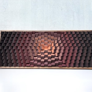 May include: A rectangular wooden wall art piece featuring a gradient of colors. The artwork is composed of numerous small, square blocks that create a textured, three-dimensional effect. The color palette transitions from dark brown to reddish-brown and orange.