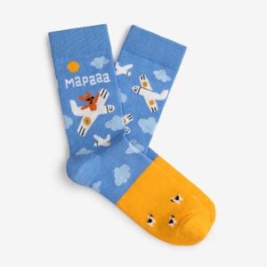 May include: A pair of blue socks with a cartoon airplane design. The socks feature a blue sky background with white clouds, a yellow sun, and white airplanes. The toe and heel are yellow. The text "Mаpааа" is printed on the side.