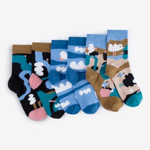 Könnte beinhalten: Sechs Paar bunte Socken mit verschiedenen abstrakten Designs. Die Socken zeigen Muster in Schwarz, Türkis, Rosa und Blautönen, mit braunen und beigen Akzenten. Sie sind auf einem weißen Hintergrund angeordnet.