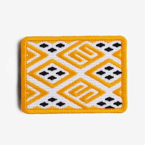 Op de afbeelding: Rechthoekige patch met een witte achtergrond en een herhalend patroon van gele ruiten en zwarte ruitvormen. De patch heeft een gele rand.