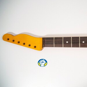 May include: A dark brown guitar neck with a light brown headstock and white dot inlays. The neck is made of rosewood and has 22 frets.