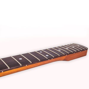 May include: A close-up of a guitar neck with a rosewood fretboard and white dot inlays. The neck is made of maple and has a natural finish.