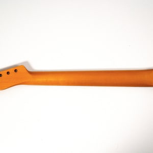 May include: Unfinished natural wood guitar neck with six tuning pegs and a logo on the back.