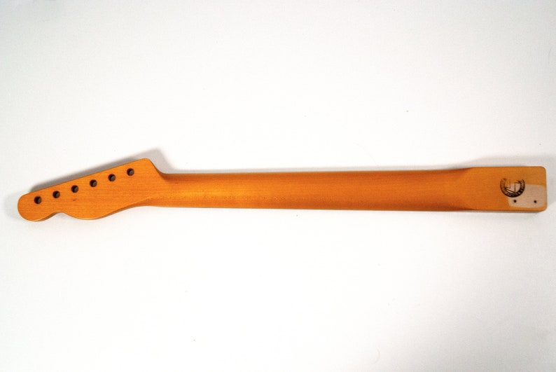 May include: Unfinished natural wood guitar neck with six tuning pegs and a logo on the back.