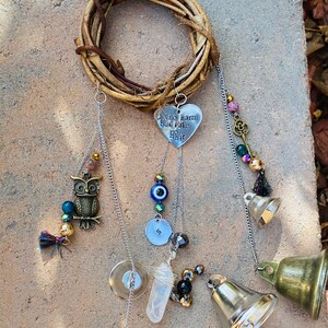 May include: A handcrafted wind chime featuring a woven twig wreath. Decorative elements include a metal heart with the text "Do no harm but take no shit", an owl charm, beads, a key charm, and brass bells.