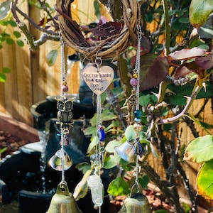 May include: A handcrafted wind chime featuring a woven grapevine ring. The chime includes a heart-shaped charm with the text "Do no harm but take no shit", along with bells, beads, and an owl charm. The wind chime is suspended from a chain.