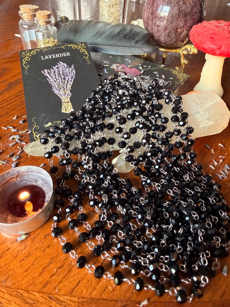 May include: A multi-strand necklace featuring faceted black beads linked together with silver-toned metal wire. The necklace is draped in several layers, creating a cascading effect of dark, reflective beads that catch the light.