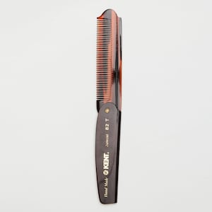 Puede incluir: Un peine Kent Sawcut 82 T, con diseño de carey y dientes finos. El peine es marrón oscuro con una parte superior curvada y un diseño articulado. El texto "Hand Made" y "KENT" está impreso en el mango.
