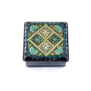 May include: A square wooden box with a black background and a blue, green, and gold geometric design. The box is decorated with intricate floral patterns.