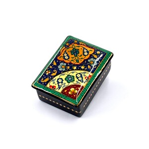 May include: A small, rectangular box with a black base and a colourful, intricate design on the lid. The design features floral patterns in shades of blue, green, yellow, and red.