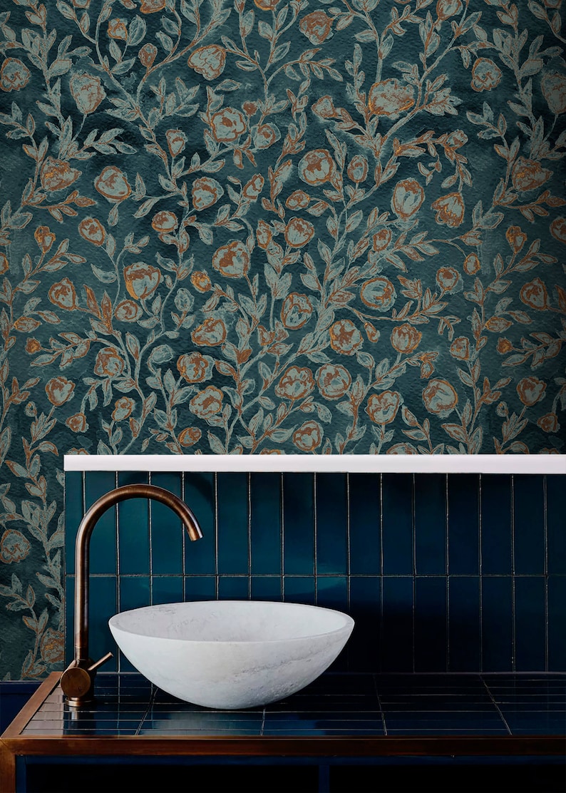 May include: A white porcelain sink with a brass tap, set against a teal tiled wall with a floral wallpaper backdrop. The wallpaper features a repeating pattern of brown and blue flowers and leaves.